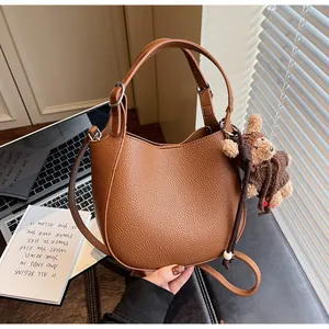 Detail of brown litchi pattern leather bucket bag with cute bear charm and silver hardware