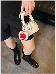 Detail of cream mini handbag with red polka dots and a cute red apple plush charm