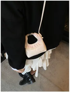 Close-up of beige faux leather shoulder bag with pink lace trim and HELAHE logo