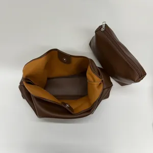 Detail view of deep brown pebbled leather tote set with yellow lining and pouch