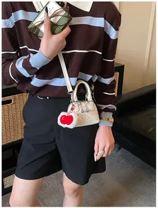 Detailansicht der weißen Shell-Tasche mit Polka-Dots, rotem Herzanhänger und Perlen
