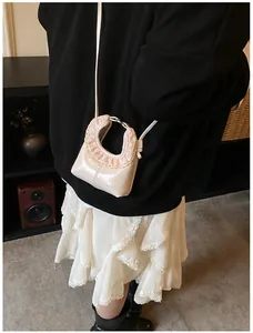 Detail of a chic cream-colored PU leather crossbody bag with delicate pink lace trim