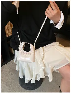 Detail of a creamy white leather mini bag featuring pink ruffles and delicate lace trim