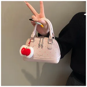 Detailed close-up of pink polka dot mini shell bag with cute red apple plush charm accessory