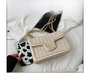 Detail of straw woven bag with pearl trim next to a phone for size reference