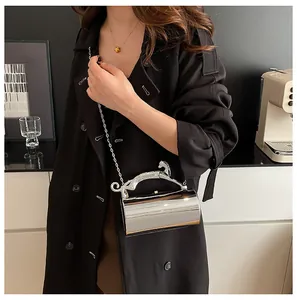 Silver cylindrical dinner clutch with leopard handle shown on a black wool coat