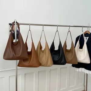 Large capacity leather hobo bags in assorted colors shown hanging on a metal display rack