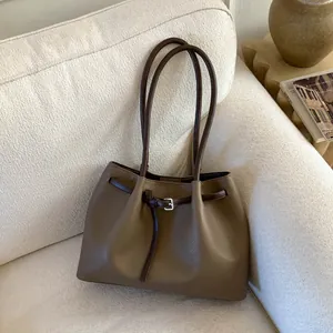 Detalle de la textura de cuero granulado y hebilla plateada en bolso tote caqui