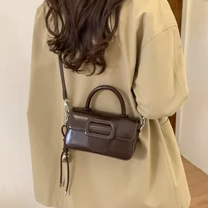 Brown leather crossbody bag with square buckle and tassel detail on female model
