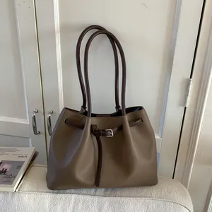 Detalle de la textura de cuero marrón con grano de lichi y hebilla plateada en el bolso