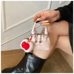 Nahaufnahme der rosa gepunkteten Muschel-Handtasche mit Plüschherz-Anhänger und Silberkette
