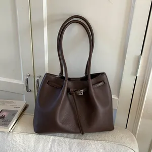 Primer plano detallado del bolso tote de cuero marrón oscuro con hebilla metálica de plata