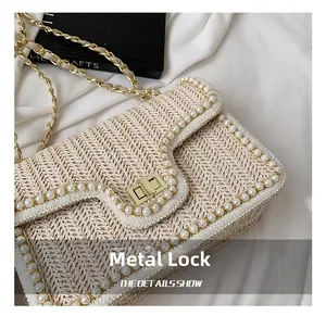 Detail shot of woven straw texture with white pearls and a gold metal lock closure