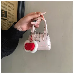 Pink shell handbag charm with red polka dots and plush cherry pendant detail