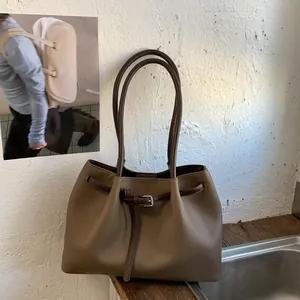 Detalle de la textura de grano litchi y hebilla metálica en el bolso tote caqui oscuro