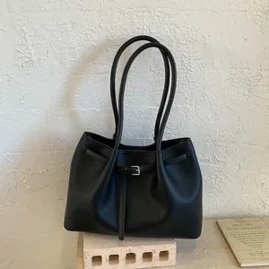 Detalle de bolso tote negro con patrón de lichi, hebilla plateada y asas de hombro