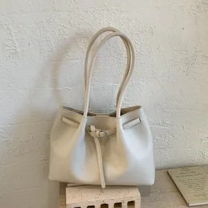 Primer plano de bolso tote beige en cuero de grano litchi con hebilla decorativa y asa