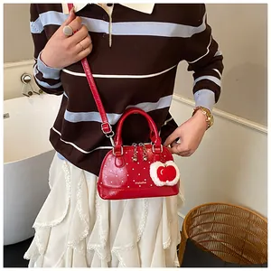 Close-up of red polka dot mini shell bag with plush apple pendant and glossy finish