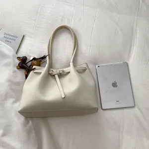 Detalle de bolso tote beige en cuero con grano de lichi y colgantes de moda