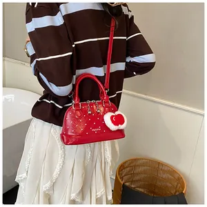 Chic red polka dot shell bag with heart charm shown on model in a lifestyle setting