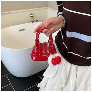 Close-up of red polka dot mini shell bag with metal zipper and plush apple charm