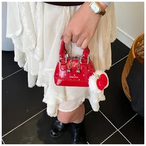 Close-up of red polka dot mini shell bag with metal chain and plush apple charm