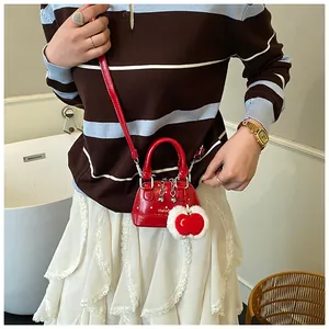 Detail shot of red patent leather mini handbag with plush heart charm and metal bell