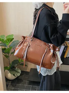 Detail of vintage brown oil leather Boston bag featuring dual zippers and metallic studs