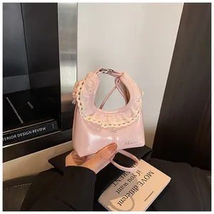 Detail of light pink patent leather shoulder bag featuring beige lace trim and brand logo
