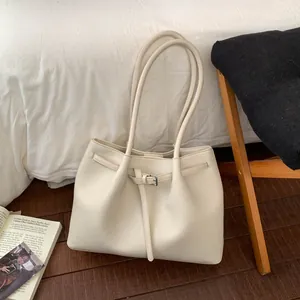 Detalle del bolso tote beige en cuero granulado con correa de hebilla metálica elegante