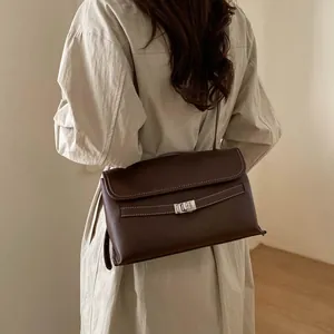 Dettaglio della borsa tote marrone scuro con chiusura a rotazione argento e cuciture bianche
