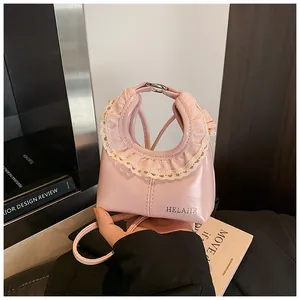 Close-up of pink patent leather bag featuring beige lace trim and HELARE logo