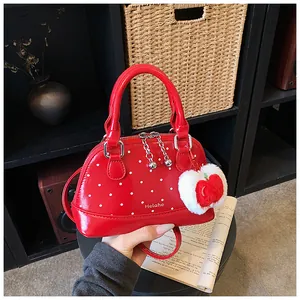 Detail of red polka dot shell bag with smooth handles and cute apple plush charm