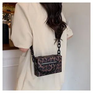 Detailed close-up of leopard print crossbody bag with thick black resin chain strap