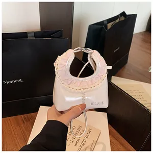 Close-up of creamy white faux leather tote with pink lace trim and embossed logo
