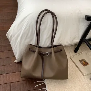 Detalle de bolso tote en cuero marrón con hebillas decorativas en un entorno acogedor