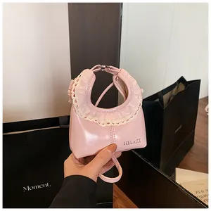 Detail of pink patent leather handbag with delicate white lace trim and silver logo