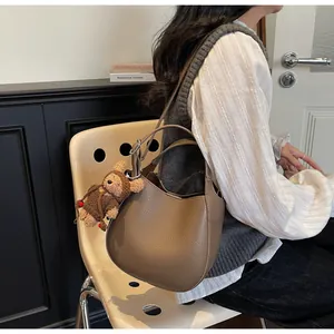 Detail of coffee brown pebble leather bucket bag with a cute bear plush keychain accessory