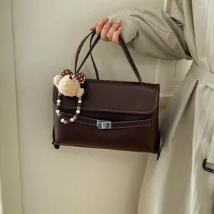 Dettaglio della borsa vintage in pelle marrone opaca con chiusura argento e ciondolo