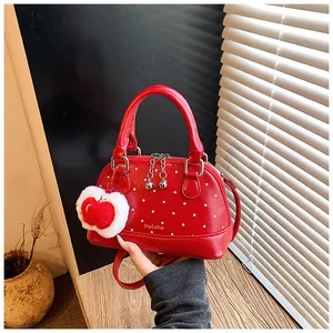 Close-up of red polka dot shell handbag with apple plush charm and Helahe logo detail