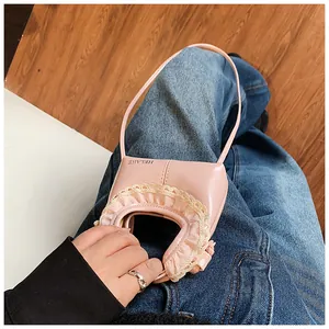 Close-up of pink glossy mini bag with white lace trim and adjustable shoulder strap
