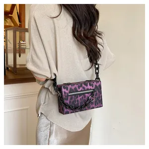 Detail of purple leopard print box bag with bold black chain strap and metal ring detail