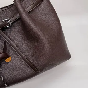 Detalle del bolso tote de cuero granulado marrón oscuro con hebilla y colgante de caballo