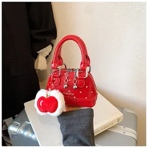 Detail of red polka dot mini handbag with glossy finish and plush apple charm