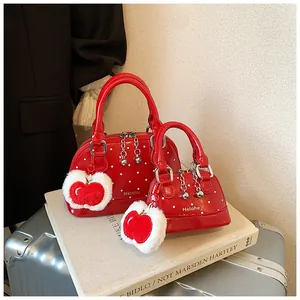 Detail of red polka dot shell bags with plush apple charms and silver metallic chains