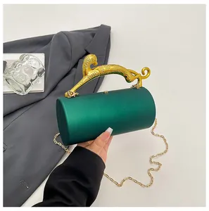 Detail of emerald green cylinder evening bag with gold leopard handle and chain strap