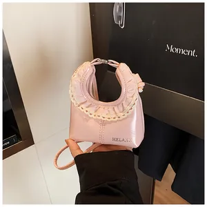 Detailed shot of pink patent leather bag featuring cream lace trim and logo detail