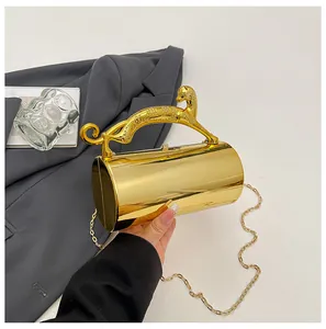 Detail of gold cylindrical evening bag featuring a sculpted leopard handle and mirror finish