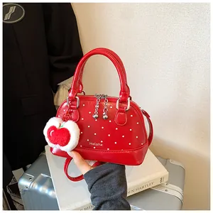Detailed view of red polka dot shell bag with apple plush pendant and dual handles