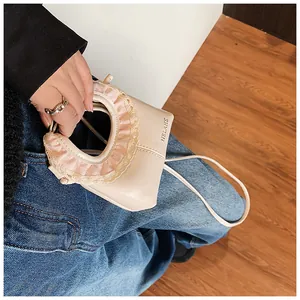 Detail of beige leather tote bag featuring pink lace trim handles and HELAHE text